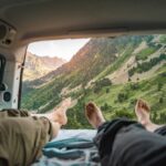 Výhľad na horskú krajinu z otvoreného kufra auta, dvaja relaxujú a užívajú si prírodu.