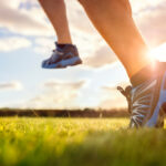 Turista si uťahuje topánky pri odpočinku počas dlhej túry v horskom prostredí.