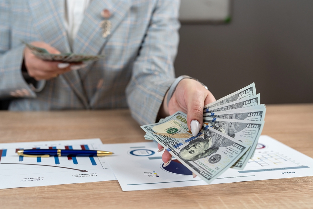 Podnikateľ počíta firemné náklady pri stole s kalkulačkou a šálkou kávy