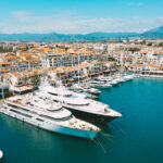 Panoramatický pohľad na jachty zakotvené v stredomorskej maríne pri západe slnka.