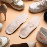 Turistické topánky s vybratou vložkou položené na kamennom podklade.