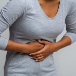 Pacient si drží oblasť žalúdka počas konzultácie s lekárom v ordinácii.