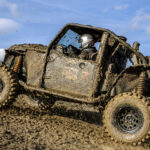 Majiteľ umýva zablatenú štvorkolku tlakovým čističom po jazde v teréne.