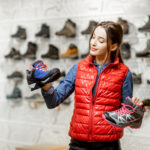 Začiatočník pri výbere a skúšaní novej turistickej obuvi v outdoorovom obchode.