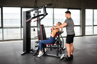 Domáci silový tréning na posilňovacej lavici s činkami a vežou