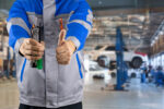 Automechanik kontrolujúci vozidlo v autoservise a zákazník preverujúci rozsah a cenu opravy automobilu.